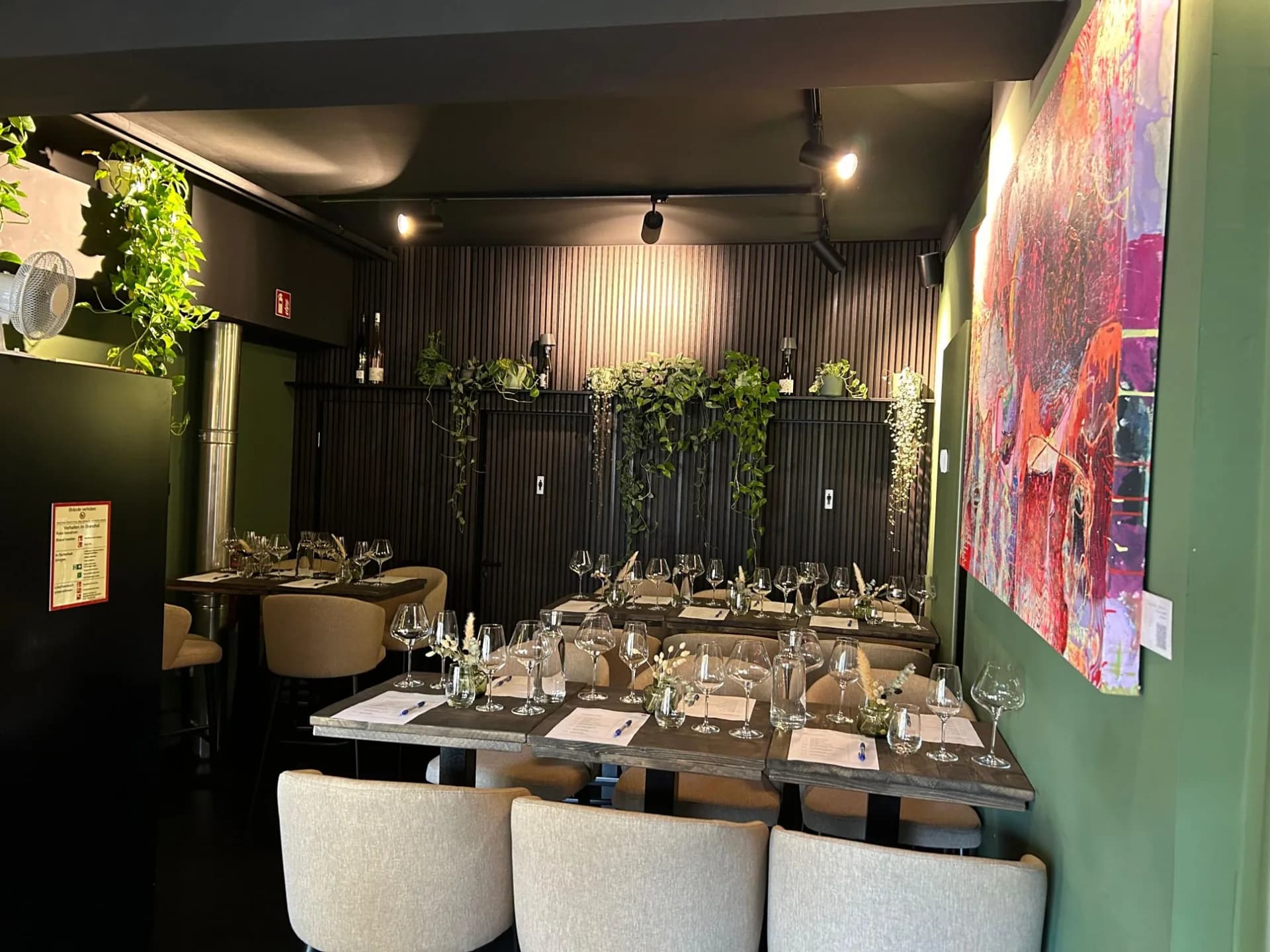 Eingedeckte Tafel im Weingrün Unionviertel mit Weingläsern, Holzlamellenwand und Rankpflanzen